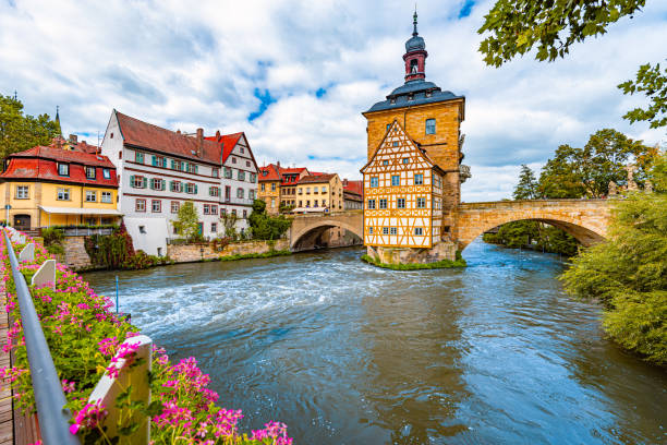 ciudad de bamberg en alemania. edificio del ayuntamiento de fondo con cielo nublado azul.  arquitectura y viajes por europa. río que fluye en primer plano. - brick european culture facade famous place fotografías e imágenes de stock