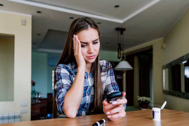 mujer joven está haciendo prueba de azúcar en la sangre en casa - hypoglycemia fotografías e imágenes de stock