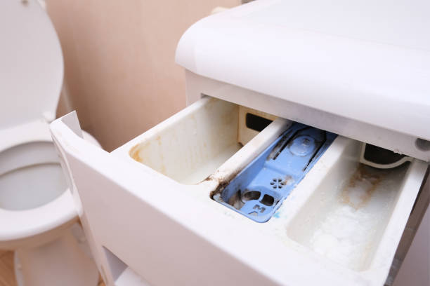 Dirty moldy washing machine detergent and fabric conditioner dispenser drawer compartment close up. Mold, rust and limescale in washing machine tray. Home appliances periodic maintenance concept.
