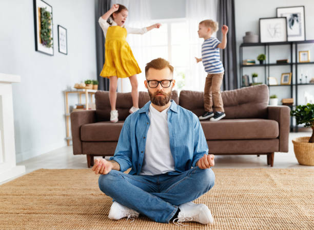 istock Father meditating in room with playful kids 1215409298