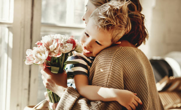 istock Happy mother with flowers hugging little son 1215410156