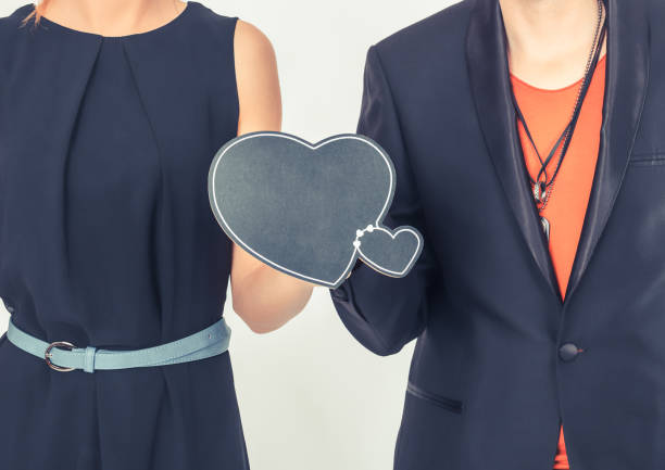 Unrecognizable couple holding heart shaped chalkboard.