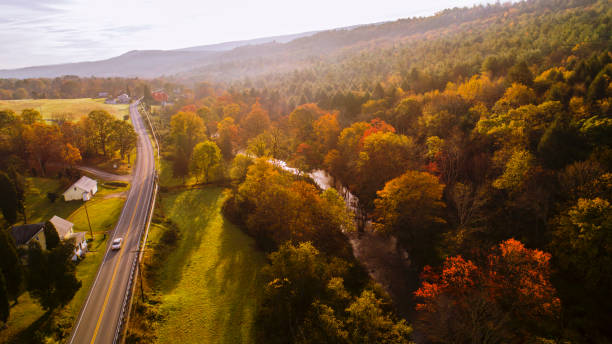 Aerial view of the country road in the forest in the mountain in the autumn foggy morning. Aerial drone view on the small town Kunkletown, Poconos, Pennsylvania, in the fall. rural main street stock pictures, royalty-free photos & images
