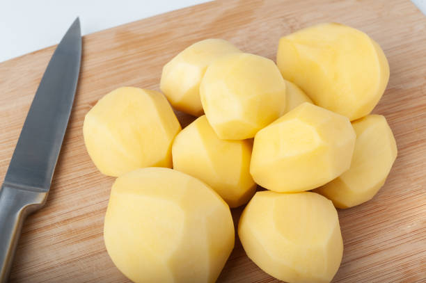 istock peeled potatoes lies on a kitchen wooden cutting board. isolate on white background 1215411129