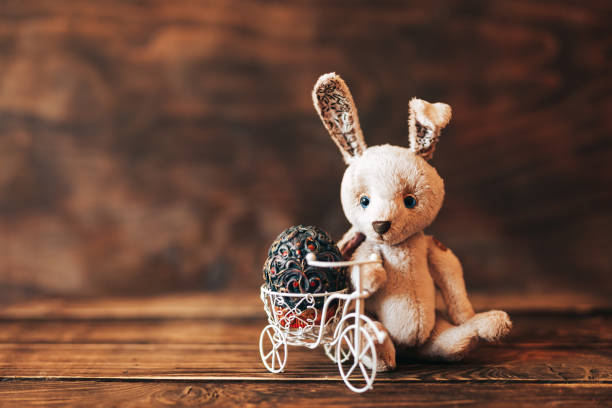Vintage egg in Easter bice, Rabbit sitting near bicycle. holiday composition on wooden background.