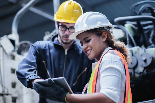 zwei wartungsingenieure männer und frauen inspizieren relaisschutzsystem mit laptop comp. sie arbeiten in einer chemiefabrik. - construction worker hardhat safety manual worker stock-fotos und bilder