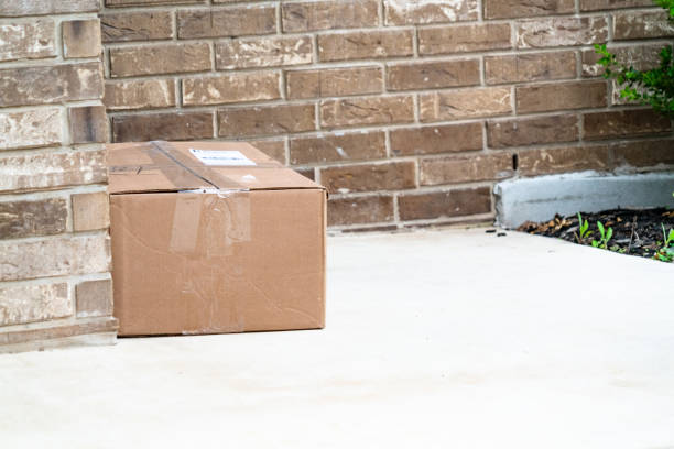 istock Cardboard box left on doorstep of brick home 1215419794
