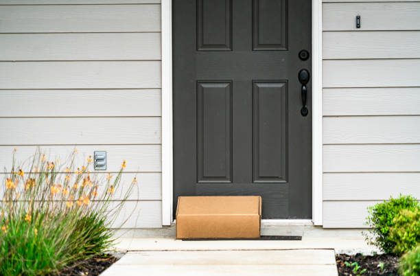 Package Delivery on Doorstep during Covid-19 Lockdown Package Delivery on Doorstep during Covid-19 pandemic , perfect suburb home with grey front door and cardboard box on door step front door stock pictures, royalty-free photos & images