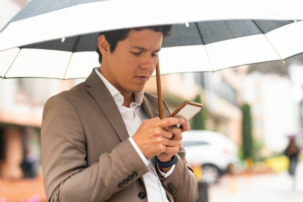 istock Young man waits for his Uber in the street while it rains 1215419900