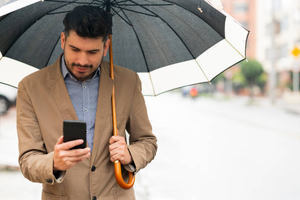 istock Young man waits for his Uber in the street while it rains 1215422341