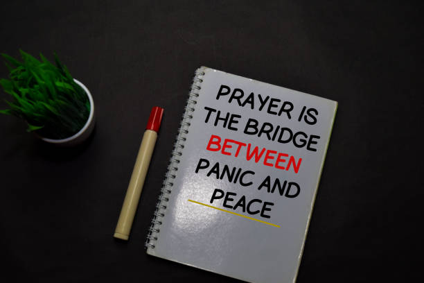 istock Prayer is the Bridge Between Panic and Peace write on a book isolated on office desk. Christian faith concept 1215423896