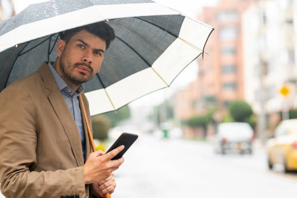 istock Young man waits for his Uber in the street while it rains 1215424691