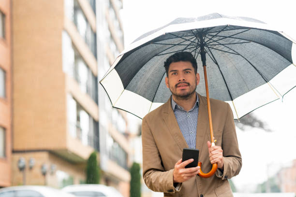 istock Young man waits for his Uber in the street while it rains 1215424987