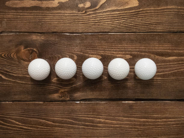 Many golf balls lined up on a wooden floor. Many golf balls lined up on a wooden floor. ゴルフ stock pictures, royalty-free photos & images