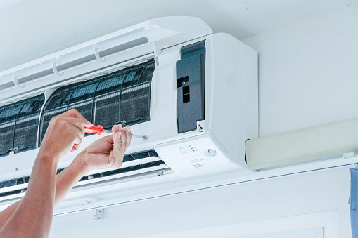 The technician under repairing the air conditioner by use screwdriver