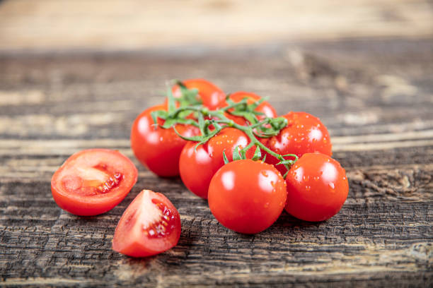 istock Fresh grape tomatoes with for use as cooking ingredients on wooden background. 1215433810
