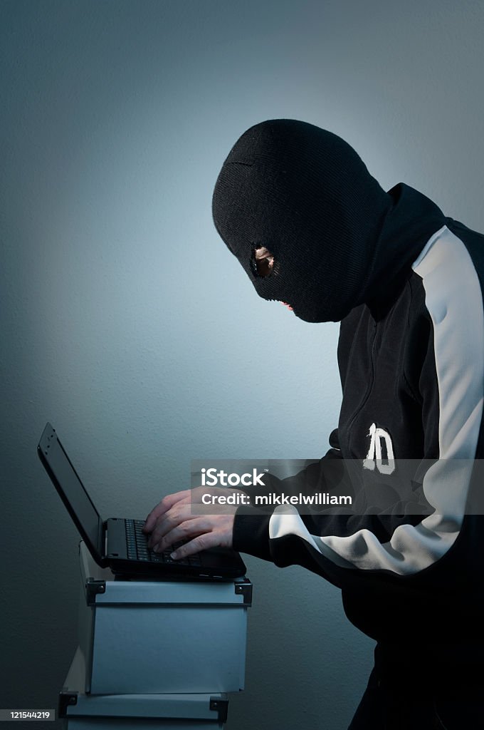 Hacker com máscara performa no laptop coberta - Foto de stock de Computador royalty-free