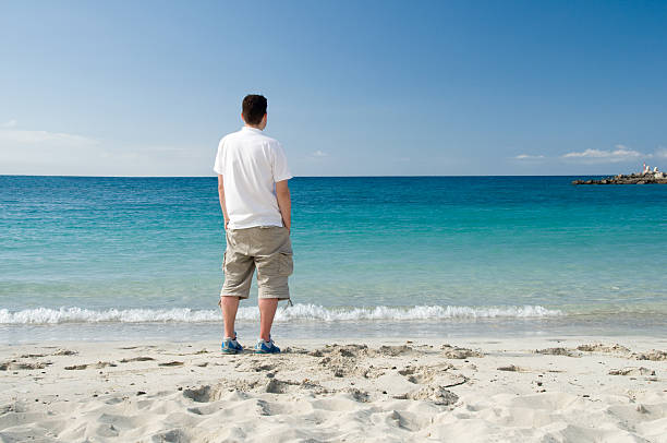 istock Man on vacation stands on beach looking at horizon 121544451
