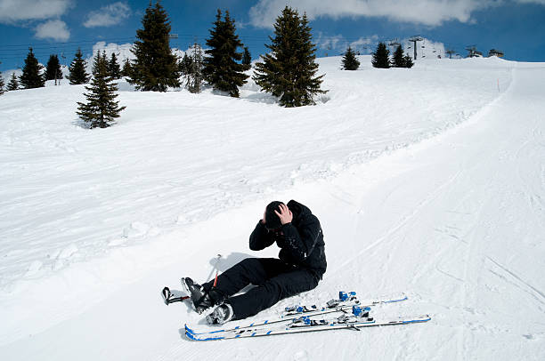 Teenager girl lying on snow at ski slope and holding her leg in pain.