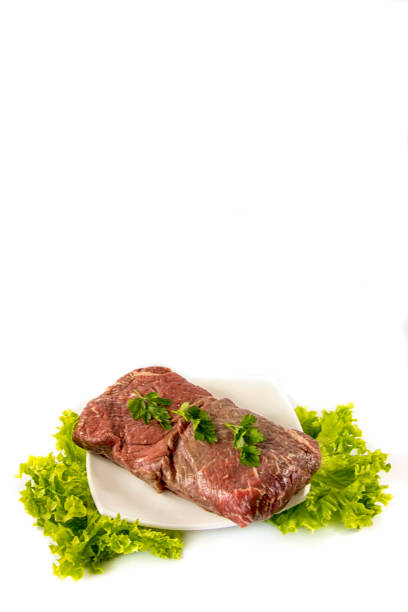 sliced piece of beef roast on a white plate, surrounded by roasted vegetable such as carrots, onions and celery