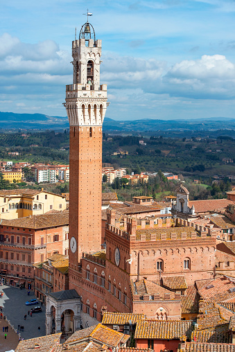 SIENA, ITALY - February 23, 2020: Mangia Tower (Torre del Mangia) at the Piazza del Campo (Campo Square), adjacent to the Palazzo Pubblico (Town Hall), Siena, Tuscany, Italy. a World Heritage Site