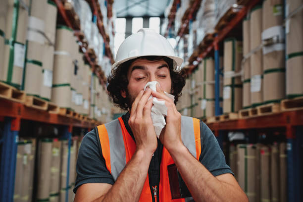 istock Young sick african warehouse worker blowing nose while working wearing safety vest 1215449847