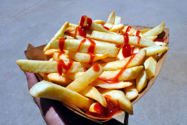 istock Man hand holding fresh potato chips with tomato sauce ready to eat 1215451544