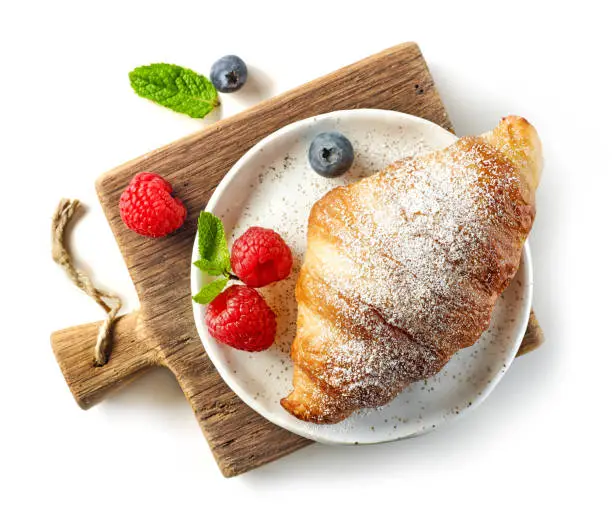 freshly baked sweet croissant decorated with fresh berries isolated on white background, top view