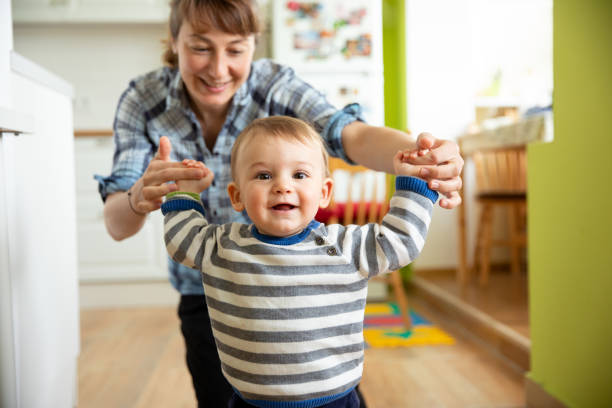 istock Young mother helping his son making his first steps at home 1215454675
