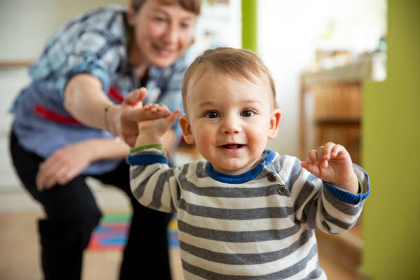 istock Young mother supporting her son with his first attempts to walk 1215454683
