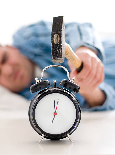 istock Tired man hits alarm clock with a big hammer 121545909