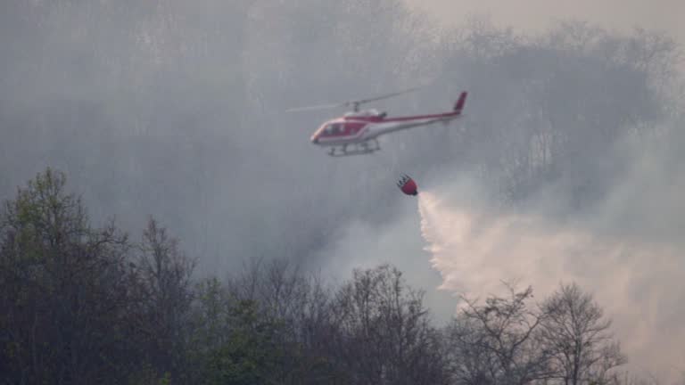 SLO MO Helicopter with firefighters throwing water to fire in the wildfire forest