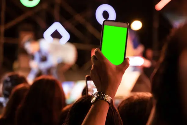 Photo of Hands of audience crowd people taking photo with mobile smart phone with green screen in party concert.