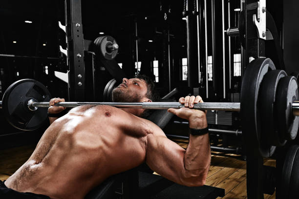 hombre joven guapo haciendo entrenamiento de prensa de banco en el gimnasio, motivación de la aptitud, estilo de vida deportivo, salud, cuerpo atlético, cuerpo positivo. grano de película, enfoque selectivo - músculos pectorales fotografías e imágenes de stock