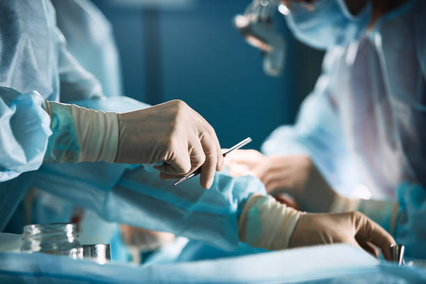 Doctor's hand with latex gloves taking stainless tweezers to help people with patience, on a white gray background. Modern medecine, life saving Doctor's hand with latex gloves taking stainless tweezers to help people with patience, on a white gray background. Modern medecine, life saving. surgery stock pictures, royalty-free photos & images