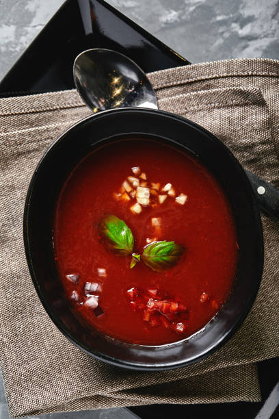 istock Tomato soup in a black bowl on a gray stone background. View from above. Copy space. Gray background. calm light. Food concept 1215466462