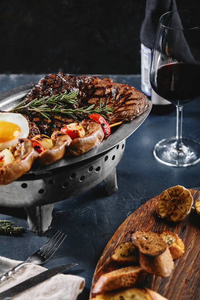 istock Grilled meat platter. Assorted delicious grilled meat with vegetables. Grilled mixed meat with pepper sauce and vegetables. Chef's hands spread meat on a plate 1215466483