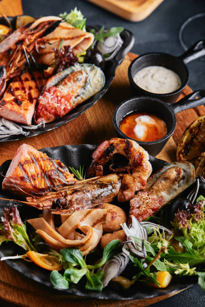 istock Assorted seafood on plates. Beautiful composition on a served seafood table, squid, shrimp, salmon steak and octopus. Food photo, low key, traditional Italian cuisine. Top view, save the space 1215466583
