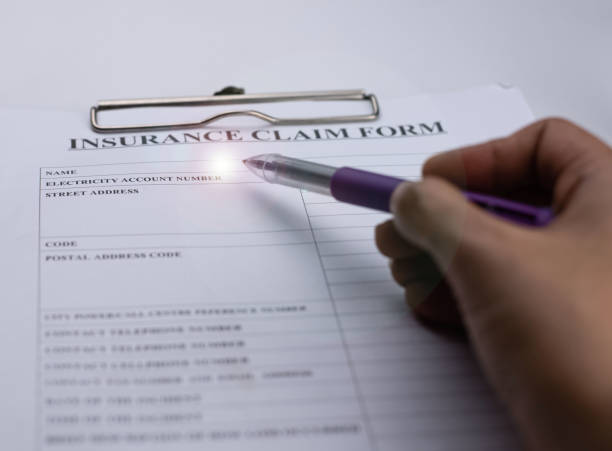 istock Blurred human hand using pen point to Insurance claim form,Lens flare effect,blurry light around 1215466969