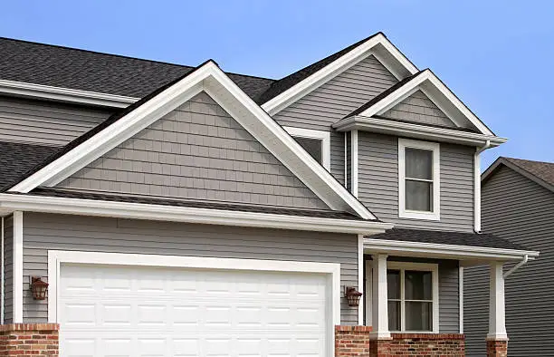 Photo of New home construction, showing siding, roofing, gutters, garage door