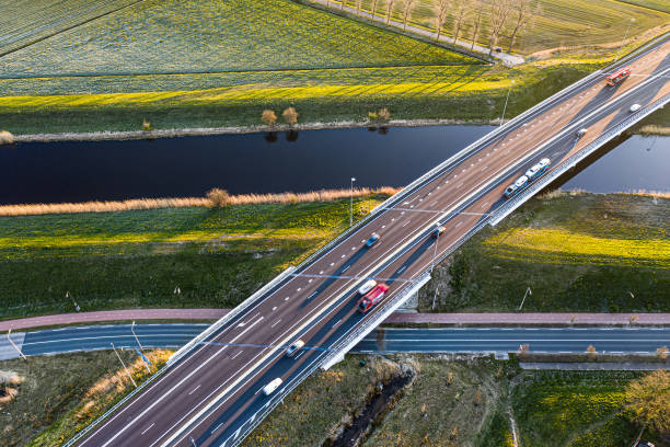 un puente viaducto cruza un canal de la autopista a59 durante el amanecer cerca de waalwijk, noord brabant, países bajos - highway traffic aerial view netherlands fotografías e imágenes de stock