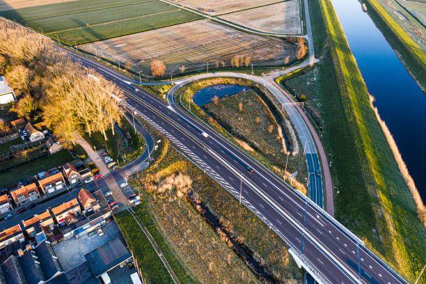 autopista a59 con salida y entrada y tráfico durante un amanecer soleado cerca de waalwijk, noord brabant, países bajos - highway traffic aerial view netherlands fotografías e imágenes de stock