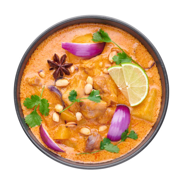 A Chicken Massaman Curry in black bowl isoated on white background. Massaman Curry is Thai Cuisine dish with chicken meat, potato, onion and many spices. Thai Food. Isolate