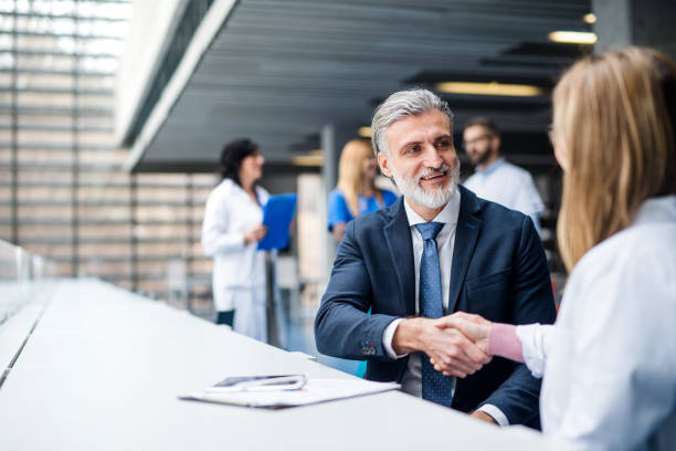 Doctors talking to pharmaceutical sales representative, shaking hands. Group of doctors talking to pharmaceutical sales representative, shaking hands. pharmaceutical industry stock pictures, royalty-free photos & images