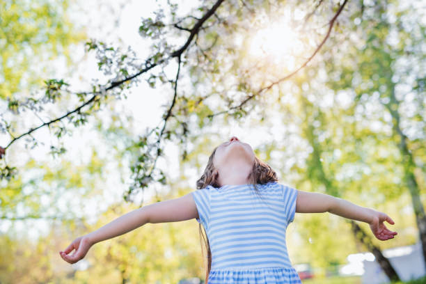 istock Small girl standing outside in spring nature, looking up. Copy space. 1215474770