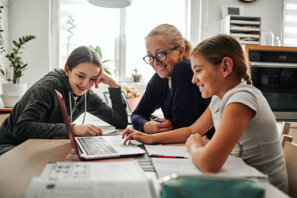 homeschooling - madre che aiuta le sue figlie a finire i compiti scolastici durante la quarantena del coronavirus - home schooling foto e immagini stock