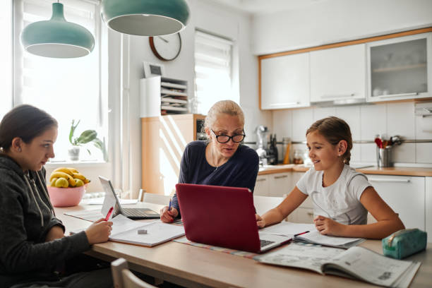 Homeschooling - Mother Helping To Her Daughters To Finish School Homework During Coronavirus Quarantine Mother helping her daughters to finish school homework during coronavirus quarantine. They are using laptop. 12 13 years pre adolescent child female blond hair stock pictures, royalty-free photos & images