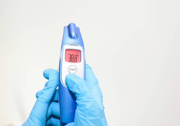Covid-19 virus and infection. Doctor wearing protective gloves and checking temperature with infrared thermometer.