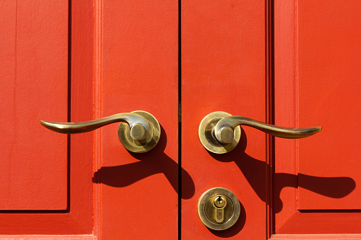 Close up old golden or brass door knob on red wood vintage door.