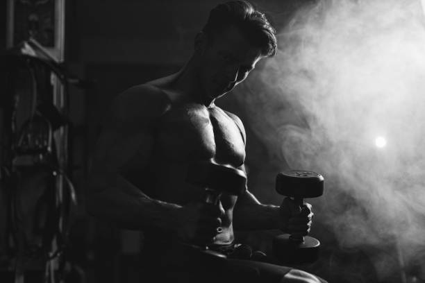 istock Attractive muscular bodybuilder with dumbbells in gym. 1215483565